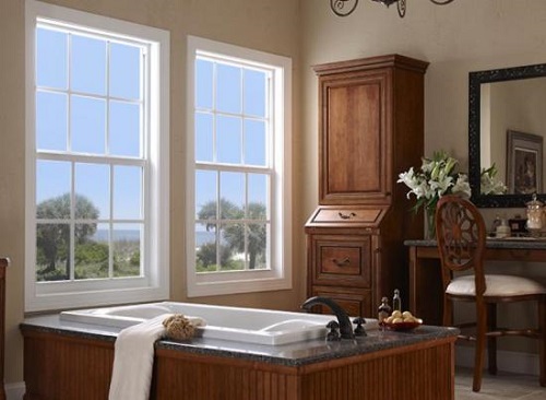 A stylish bathroom with a standalone tub, sitting table, and large windows.