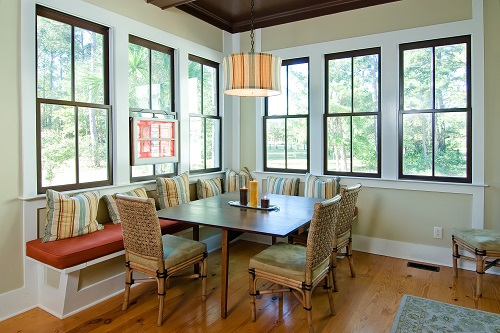 Dining room framed in double-hung windows overlooking a yard with trees.