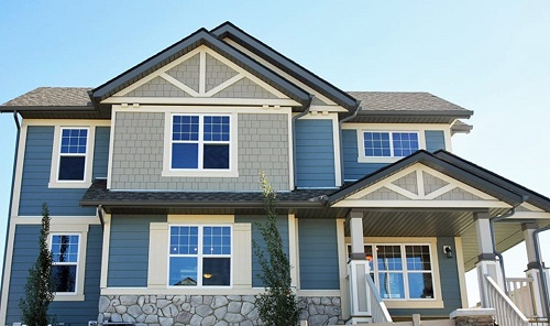 A large house with blue fiber cement siding, gray shingle siding, and white trim.