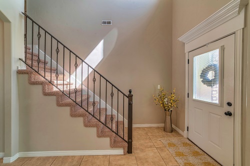 House interior with glass paned white front door and stairs at the entryway.