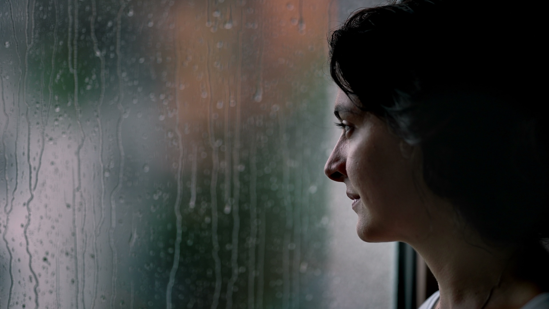 Woman standing by a window during rainy weather