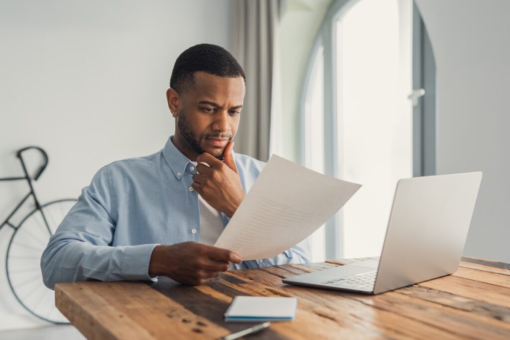 Homeowner reviewing window paperwork at a table with a laptop