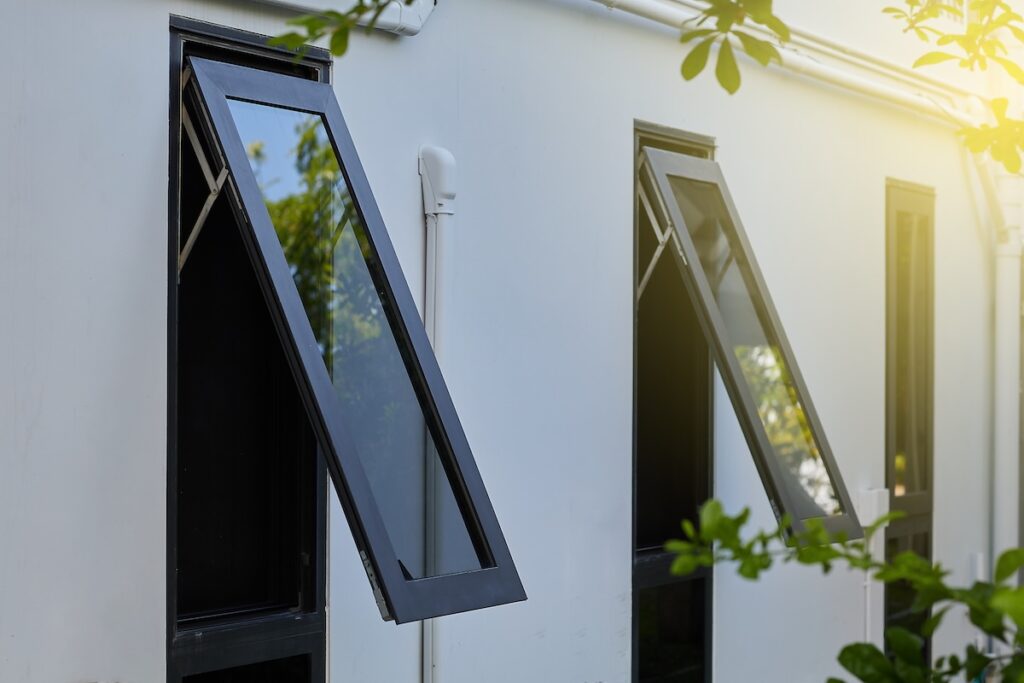 Black awning windows opened outward on a modern exterior wall