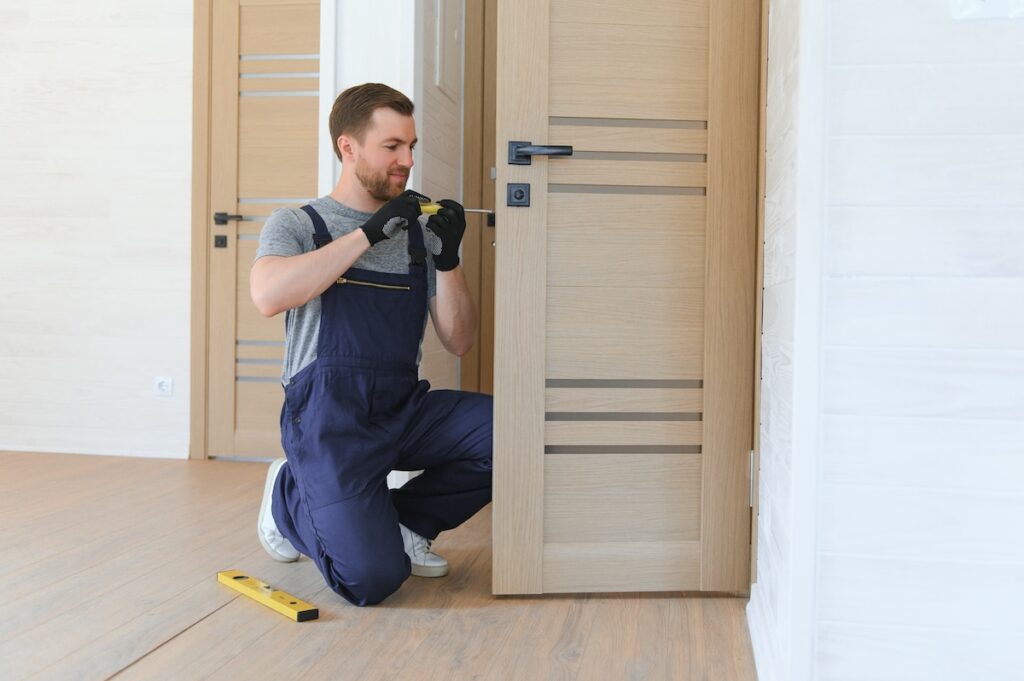 Installer adjusting an interior wood door with a screwdriver