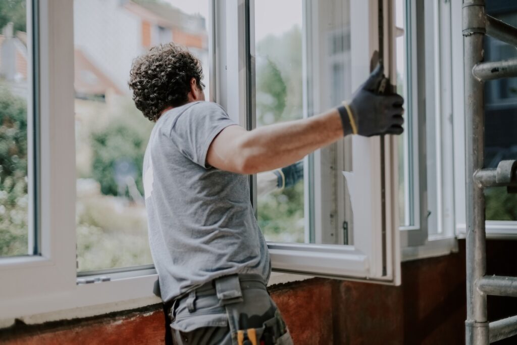 Window installer repairing a window frame inside a home