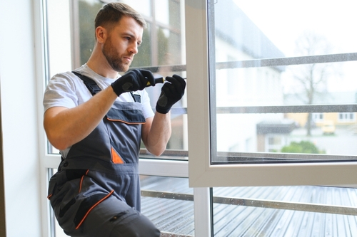 Window technician adjusting and inspecting a white casement window during service visit